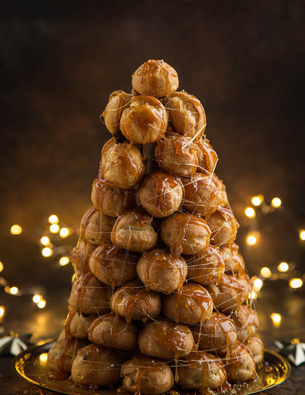 croquembouche, festive profiteroles cake with caramel for Christmas, selective focus, dark background