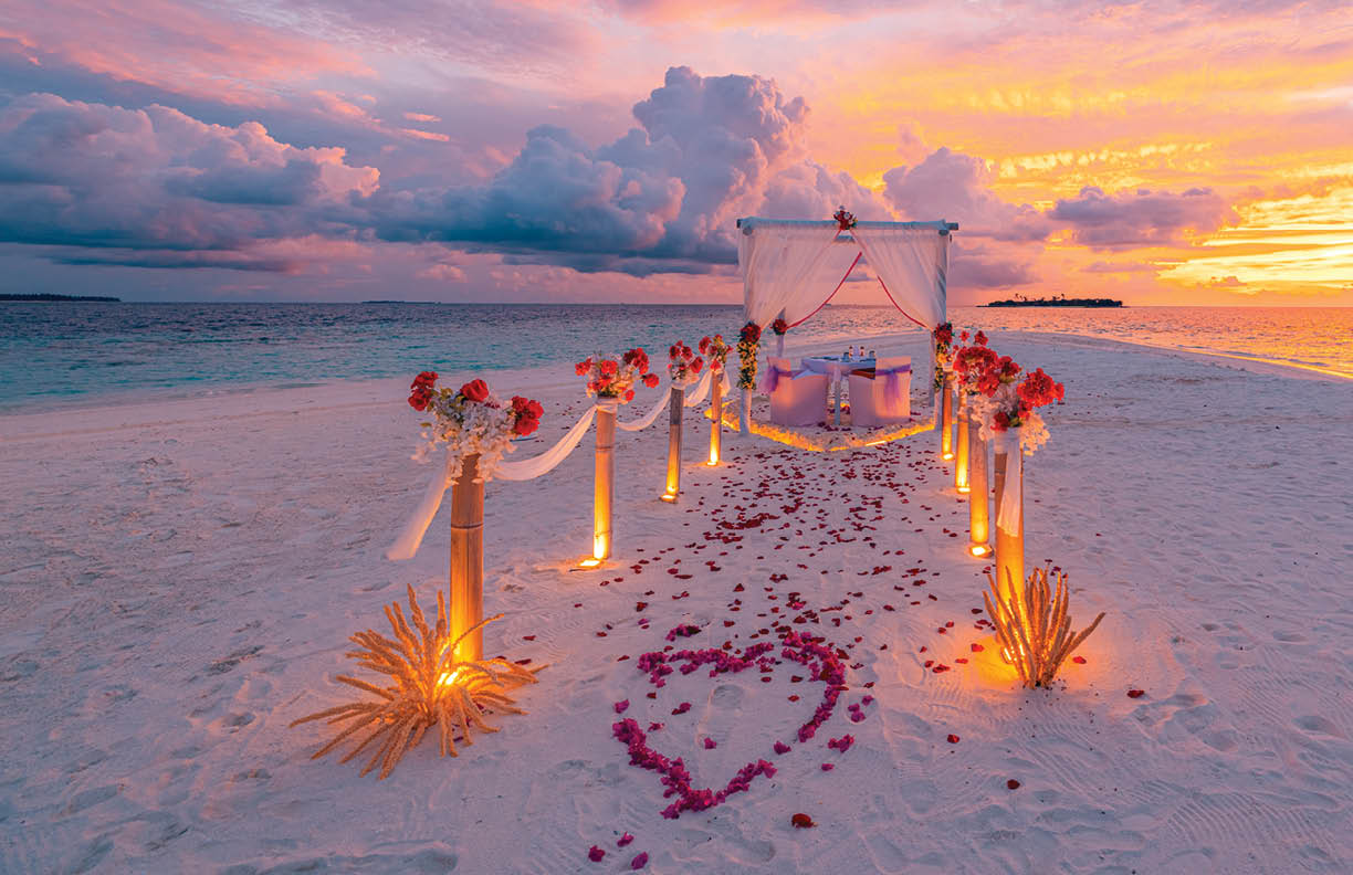Romantic beach wedding sunset scene with candles tropical ocean view calm sea dreamy sky clouds couple celebration honeymoon anniversary scenic destination love atmosphere summer travel background