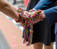 Bride and groom together, tied by the hands with a colorful rope doing a ritual, on the wedding day. Wedding concept