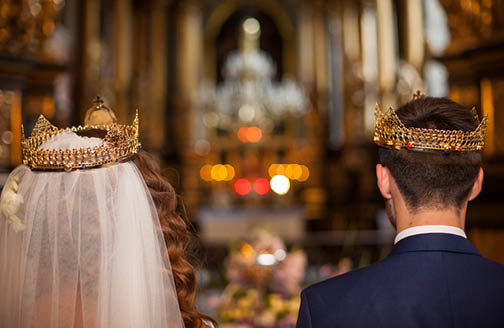 Fairytale couple, bride and groom in crowns during wedding ceremony in church