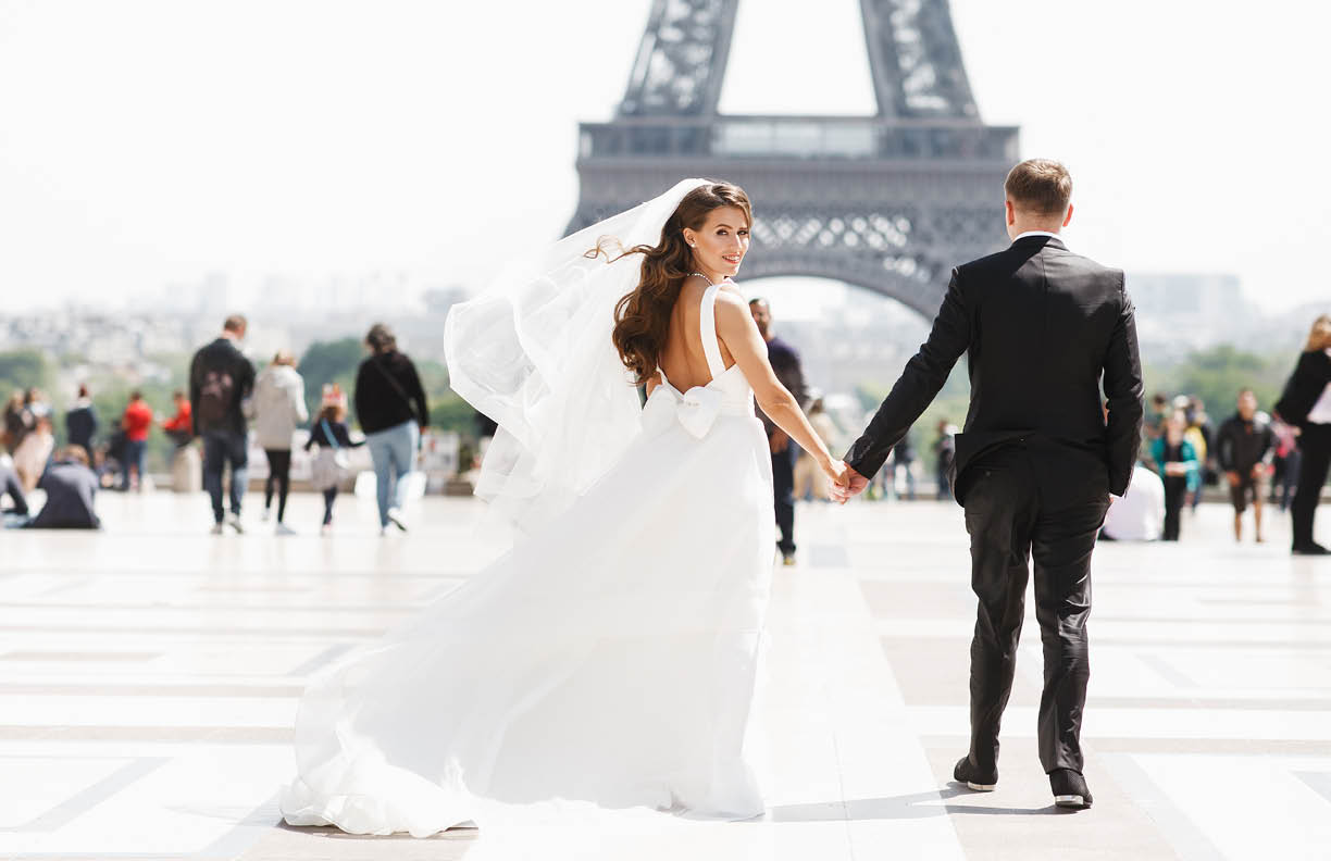 Beautiful wedding couple has fun posing on the square before the Eiffel Tower in Paris