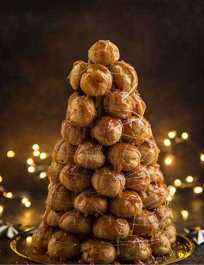 croquembouche, festive profiteroles cake with caramel for Christmas, selective focus, dark background