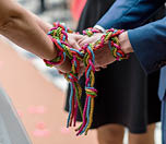 Bride and groom together, tied by the hands with a colorful rope doing a ritual, on the wedding day. Wedding concept