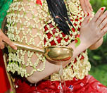 A traditional Indonesian siraman ritual, where water is poured over a bride-to-be, symbolizing purification and blessings before the wedding, performed with floral attire and a brass ladle.