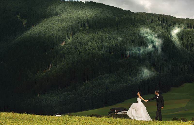Beautiful stylish Asians bride and groom walking in alpine meadows in Italy, Trentino Alto Adige