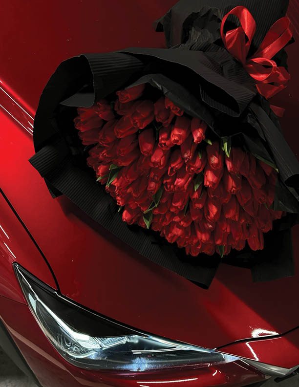 A large bouquet of bright red tulips on a red car